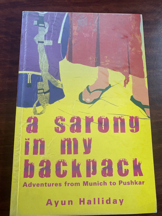 Book cover of 'A Sarong in My Backpack' by Ayun Halliday on a wooden surface