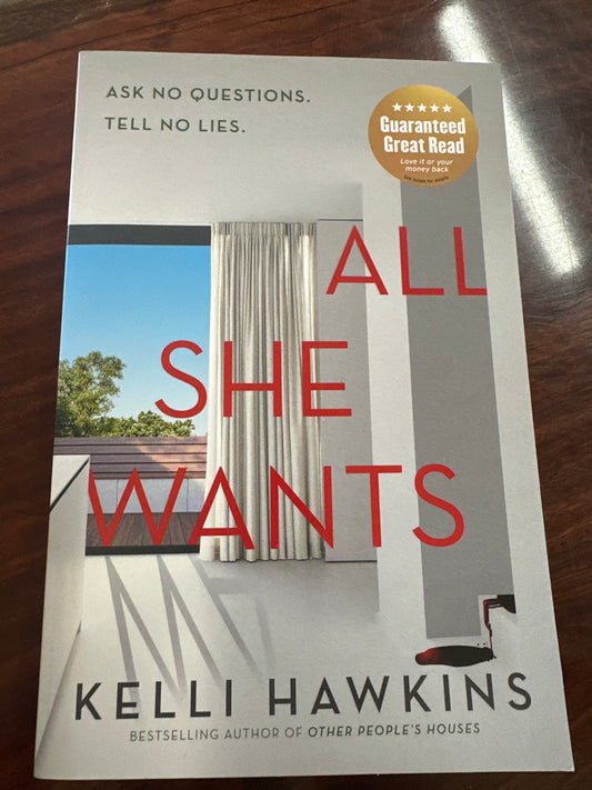Book titled 'All She Wants' by Kelli Hawkins on a wooden surface