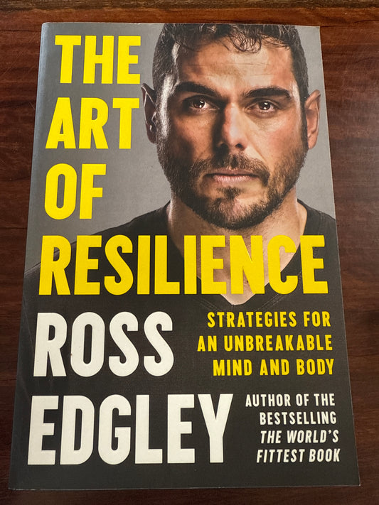 Book cover of 'The Art of Resilience' by Ross Edgley on a wooden surface