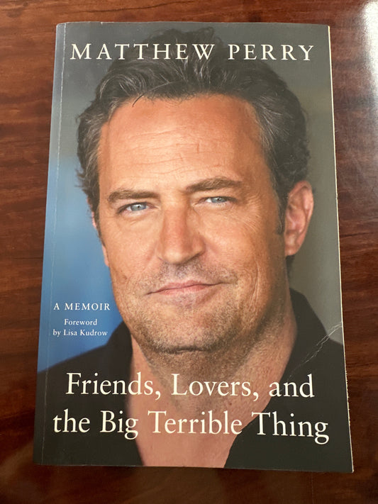 Book cover of 'Friends, Lovers, and the Big Terrible Thing' by Matthew Perry on a wooden surface.