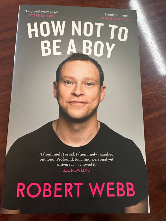 Book titled 'How Not to Be a Boy' by Robert Webb on a wooden surface