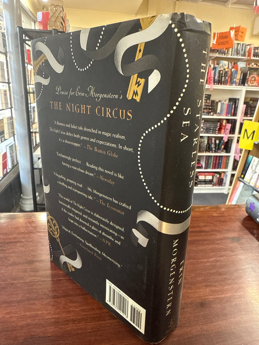 Book titled 'The Starless Sea' by Erin Morgenstern back cover on a wooden surface