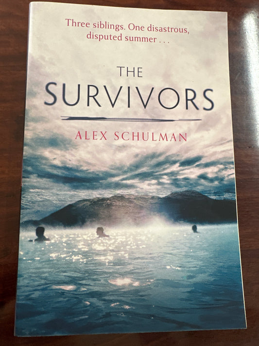 Book cover of 'The Survivors' by Alex Schulman on a wooden surface