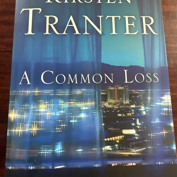 Book titled 'A Common Loss' by Kirsten Tranter on a wooden surface