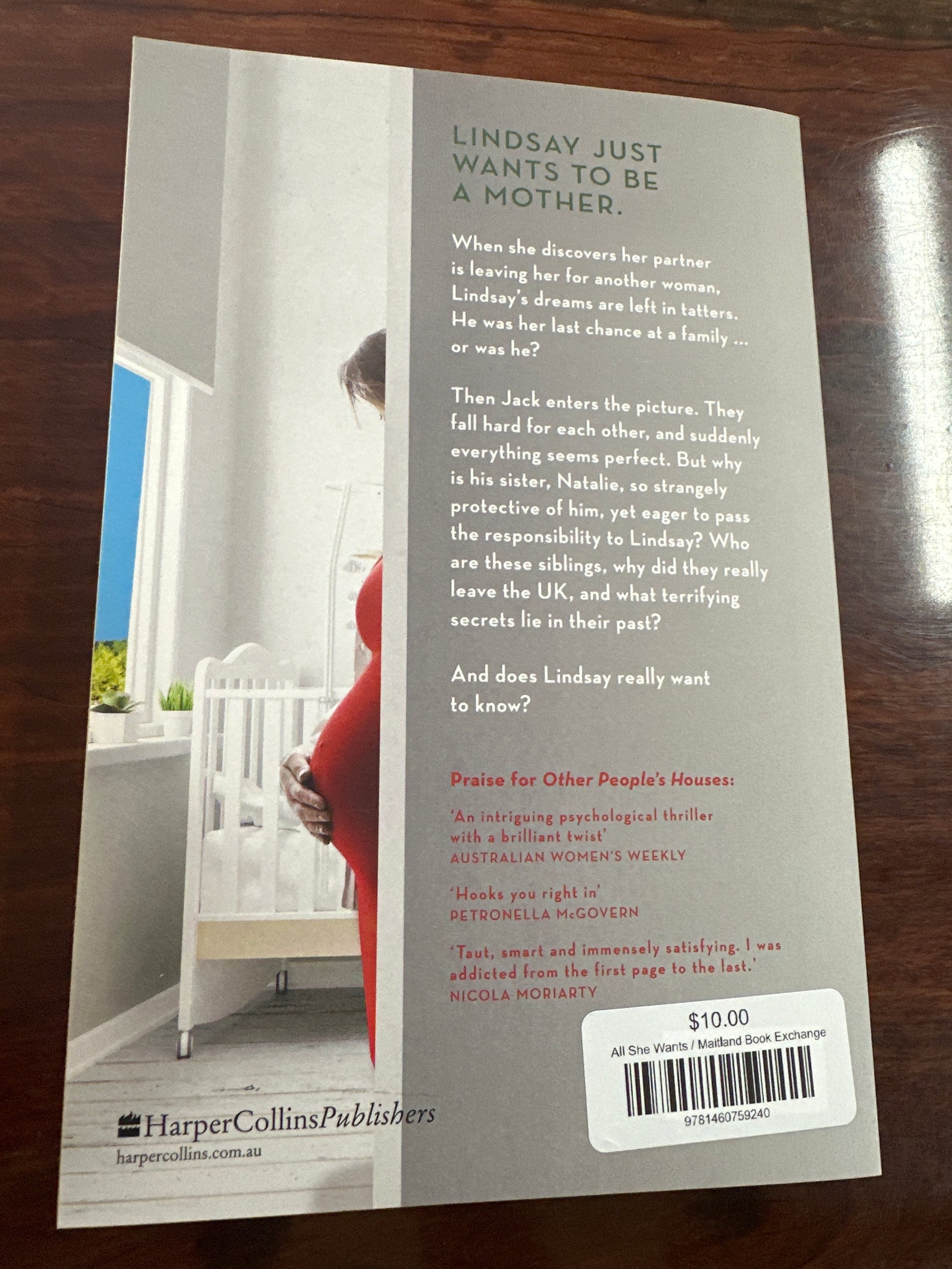 Back cover of Book titled 'All She Wants' by Kelli Hawkins on a wooden surface