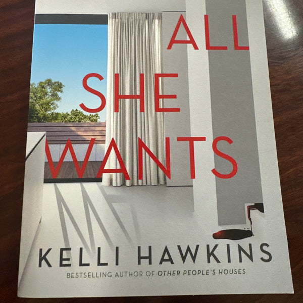Book titled 'All She Wants' by Kelli Hawkins on a wooden surface