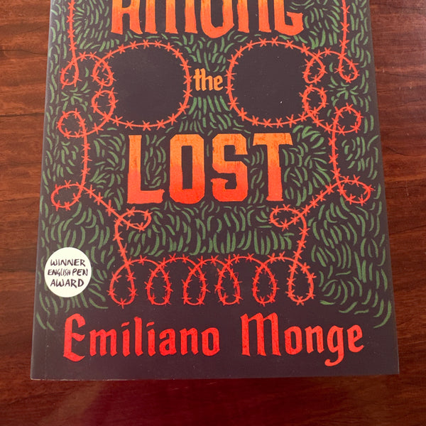 Book titled 'Among the Lost' by Emiliano Monge on a wooden surface
