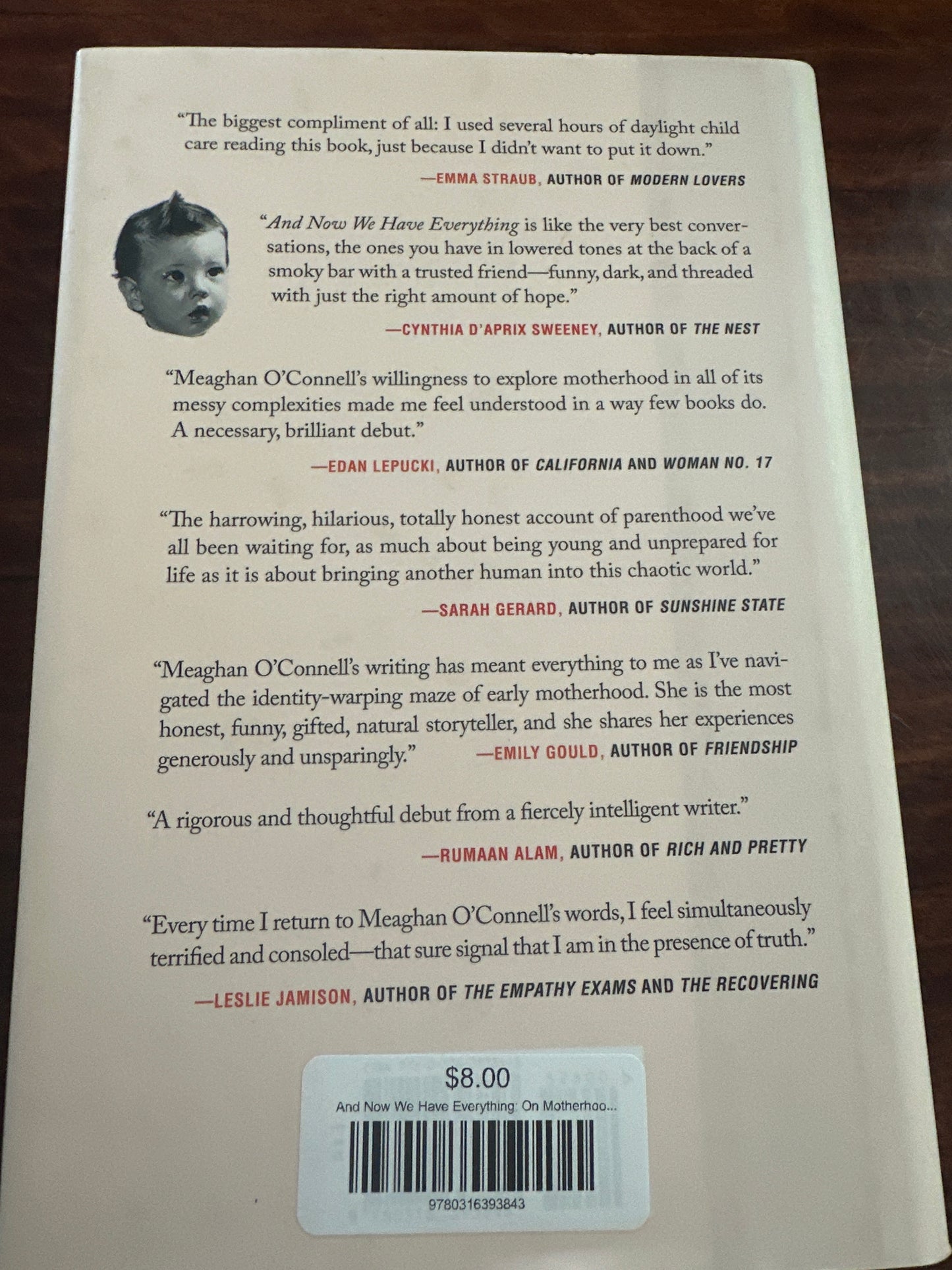 And Now We Have Everything Book back cover with text and a barcode on a wooden surface