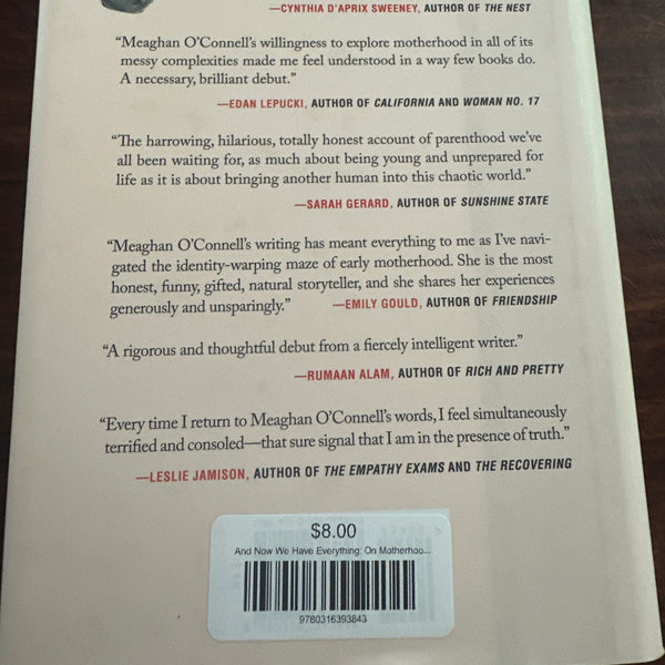 And Now We Have Everything Book back cover with text and a barcode on a wooden surface