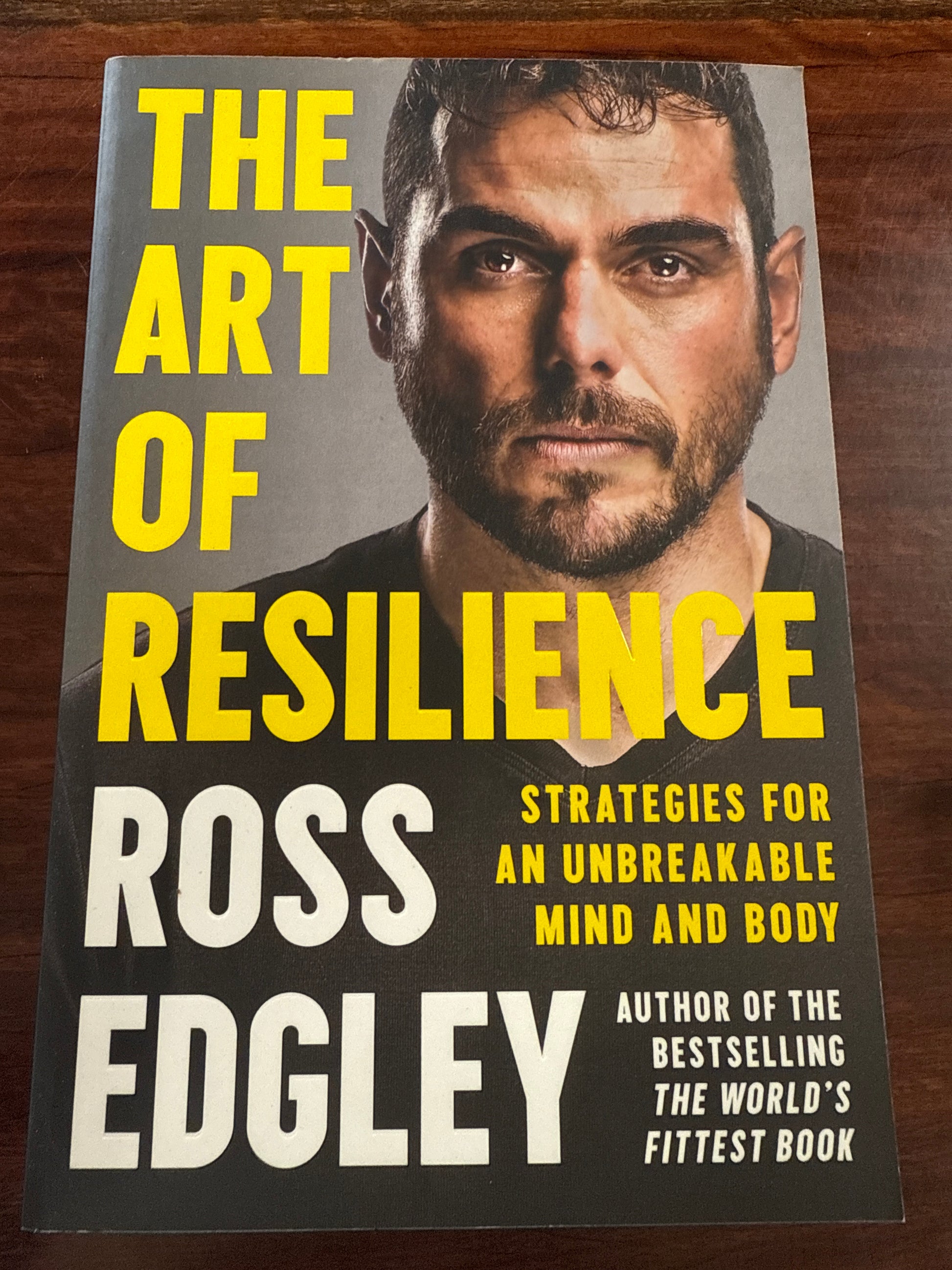 Book cover of 'The Art of Resilience' by Ross Edgley on a wooden surface