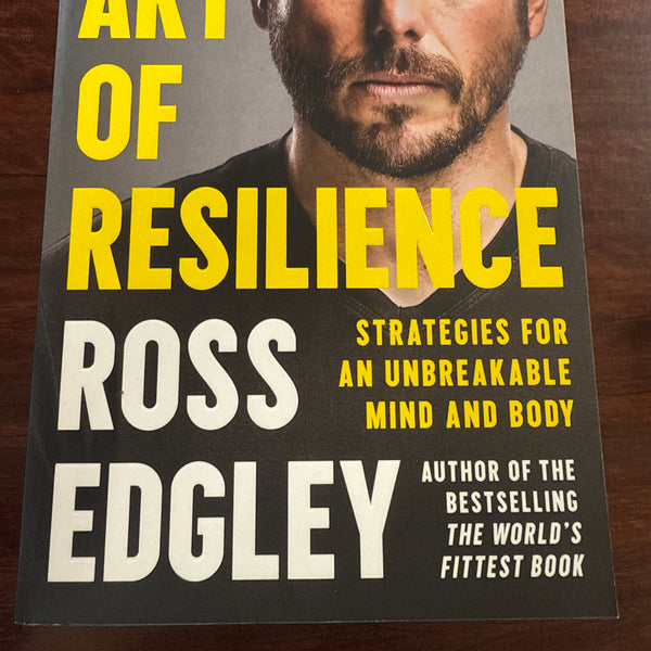 Book cover of 'The Art of Resilience' by Ross Edgley on a wooden surface