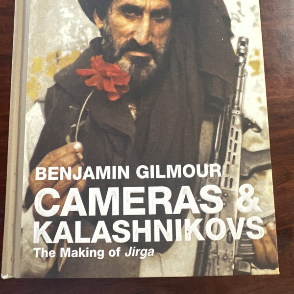 Book cover of 'Cameras & Kalashnikovs' by Benjamin Gilmour on a wooden surface