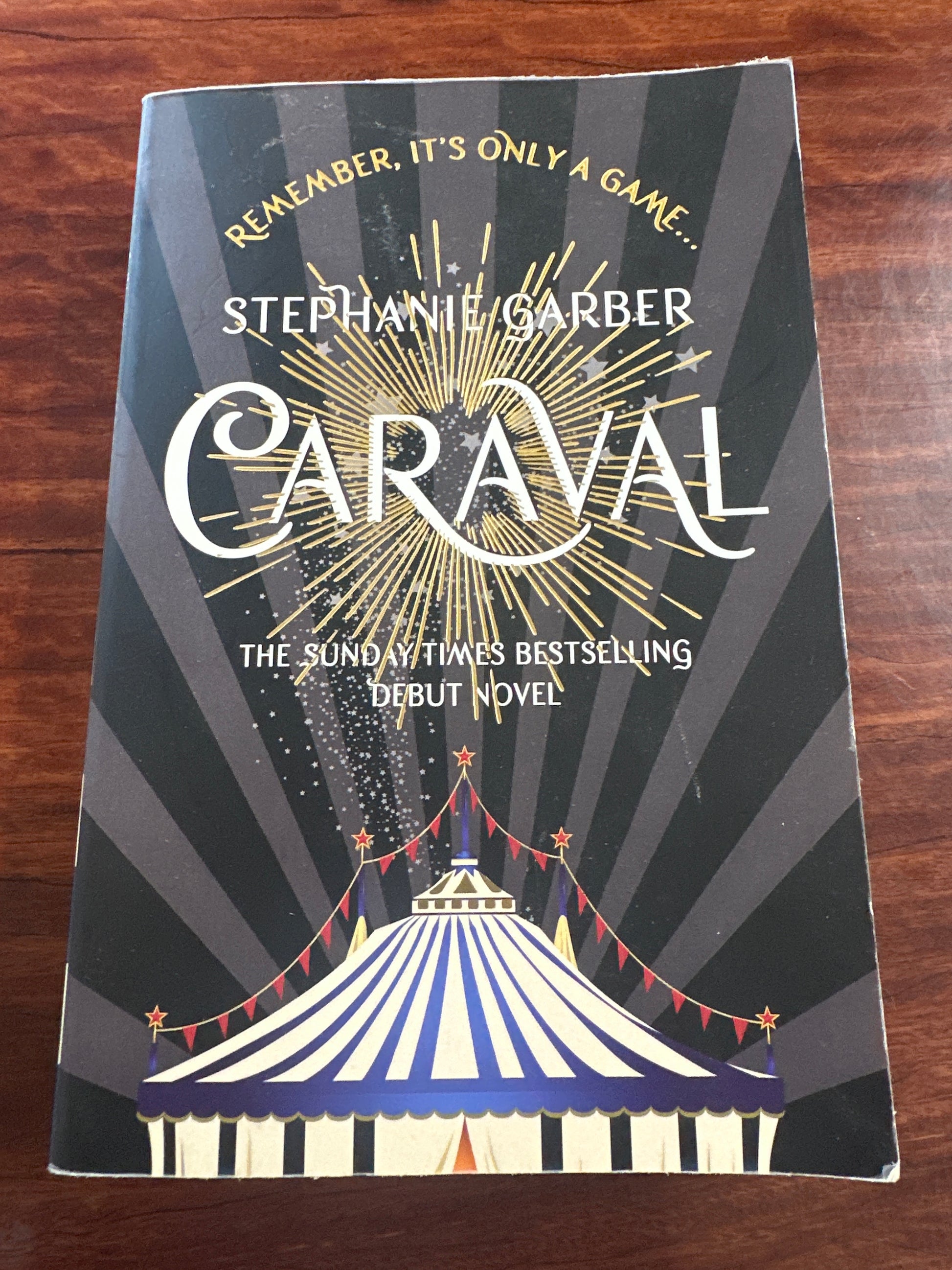 Book cover of 'Caraval' by Stephanie Garber on a wooden surface