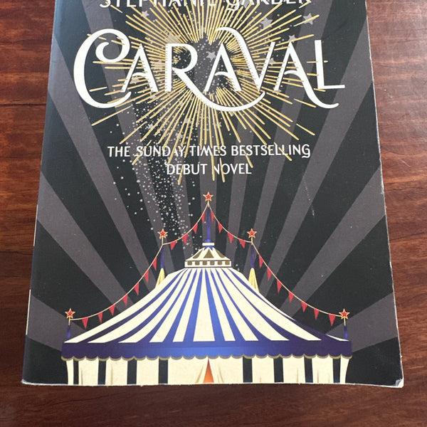 Book cover of 'Caraval' by Stephanie Garber on a wooden surface