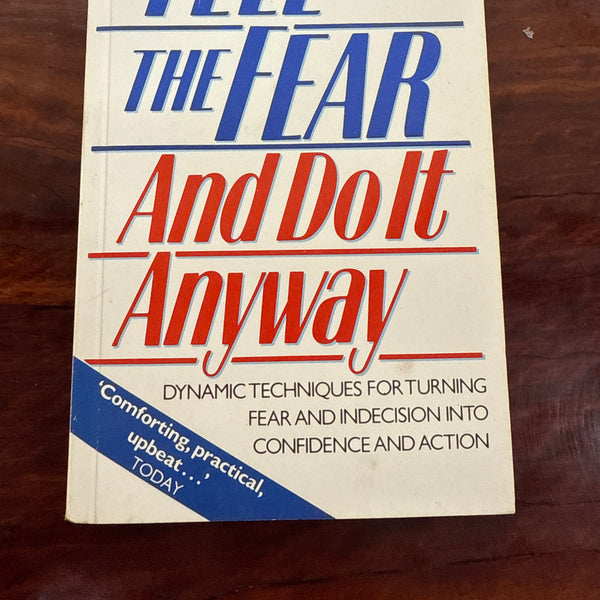 Book titled 'Feel the Fear and Do It Anyway' by Susan Jeffers on a wooden surface