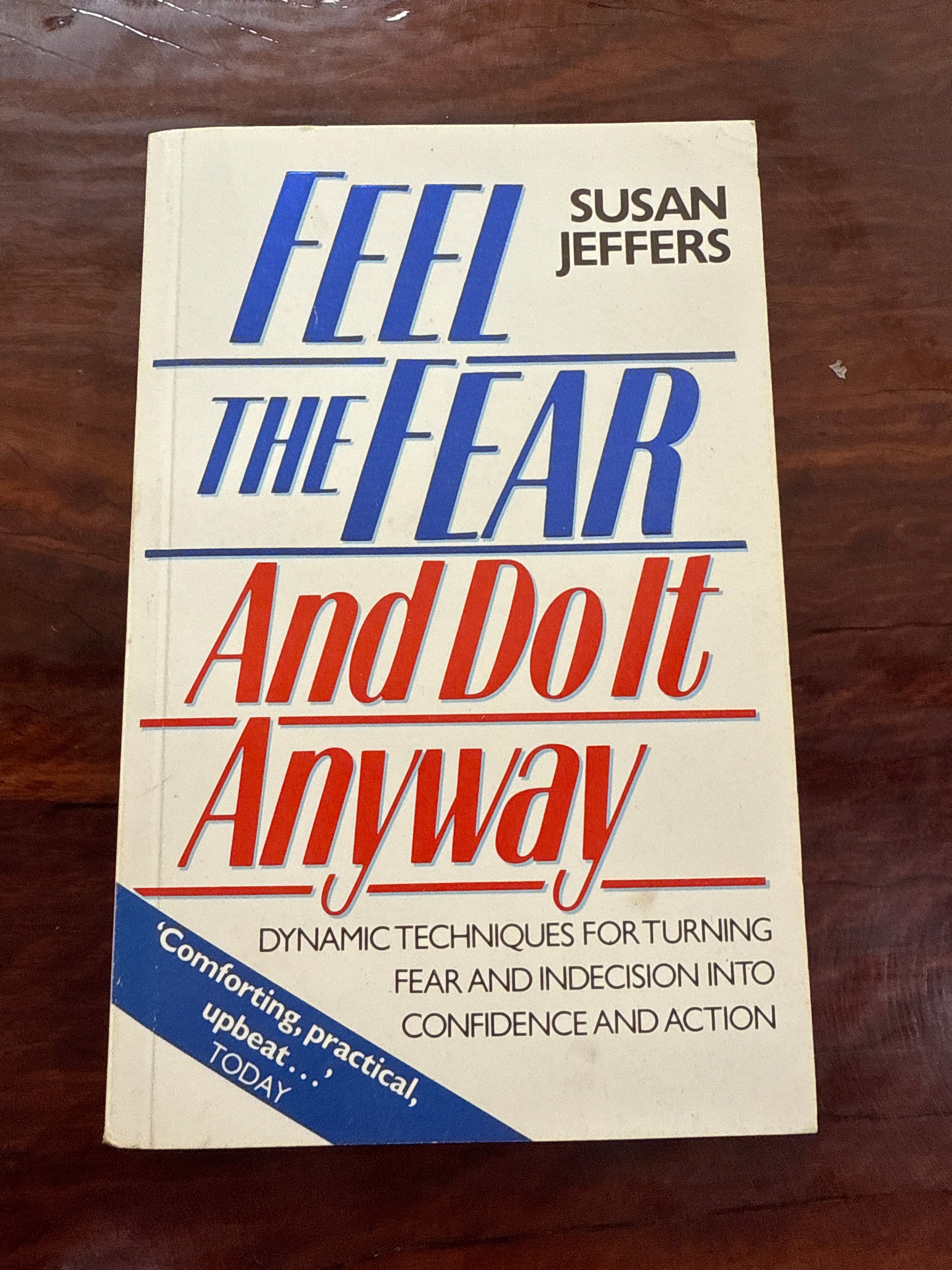 Book titled 'Feel the Fear and Do It Anyway' by Susan Jeffers on a wooden surface