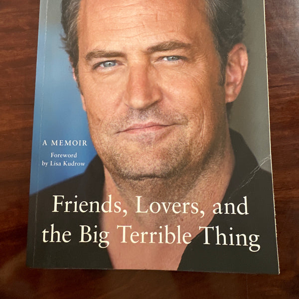 Book cover of 'Friends, Lovers, and the Big Terrible Thing' by Matthew Perry on a wooden surface.