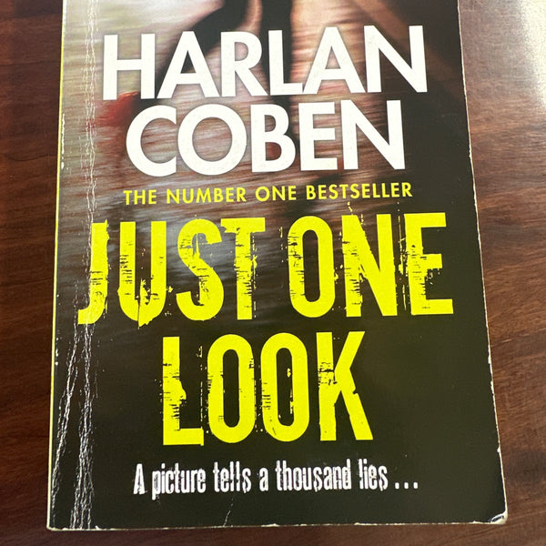 Book cover of 'Just One Look' by Harlan Coben on a wooden surface