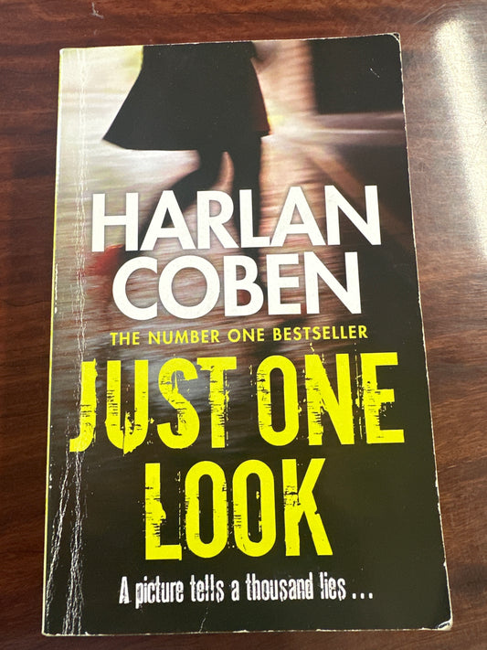 Book cover of 'Just One Look' by Harlan Coben on a wooden surface