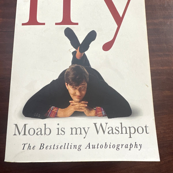 Book cover of 'Moab is my Washpot' by Stephen Fry on a wooden surface