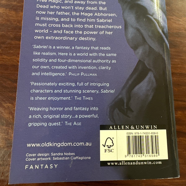 Back cover of Sabriel' by Garth Nix on a wooden surface