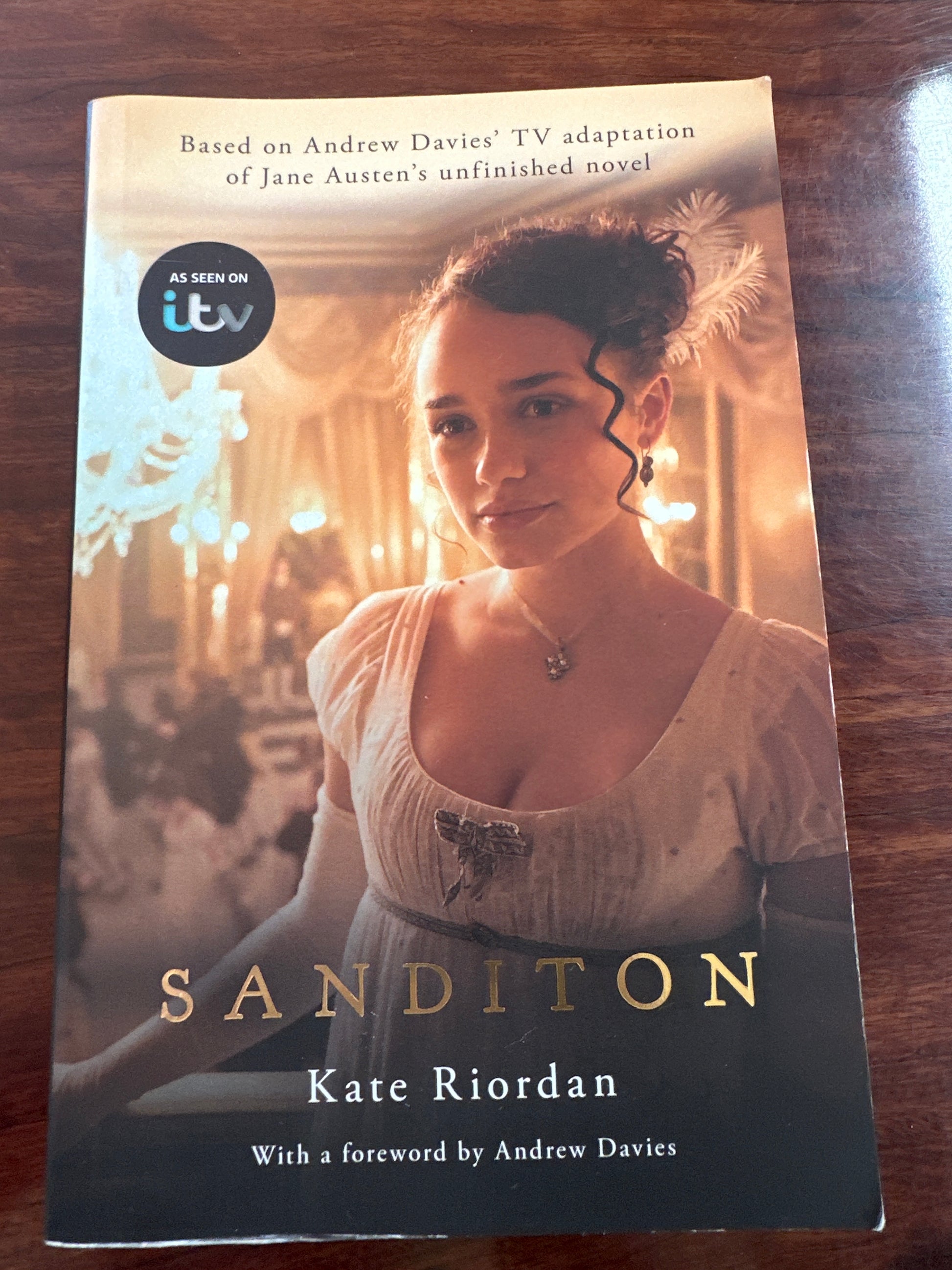 Book cover of 'Sanditon' by Kate Riordan on a wooden surface