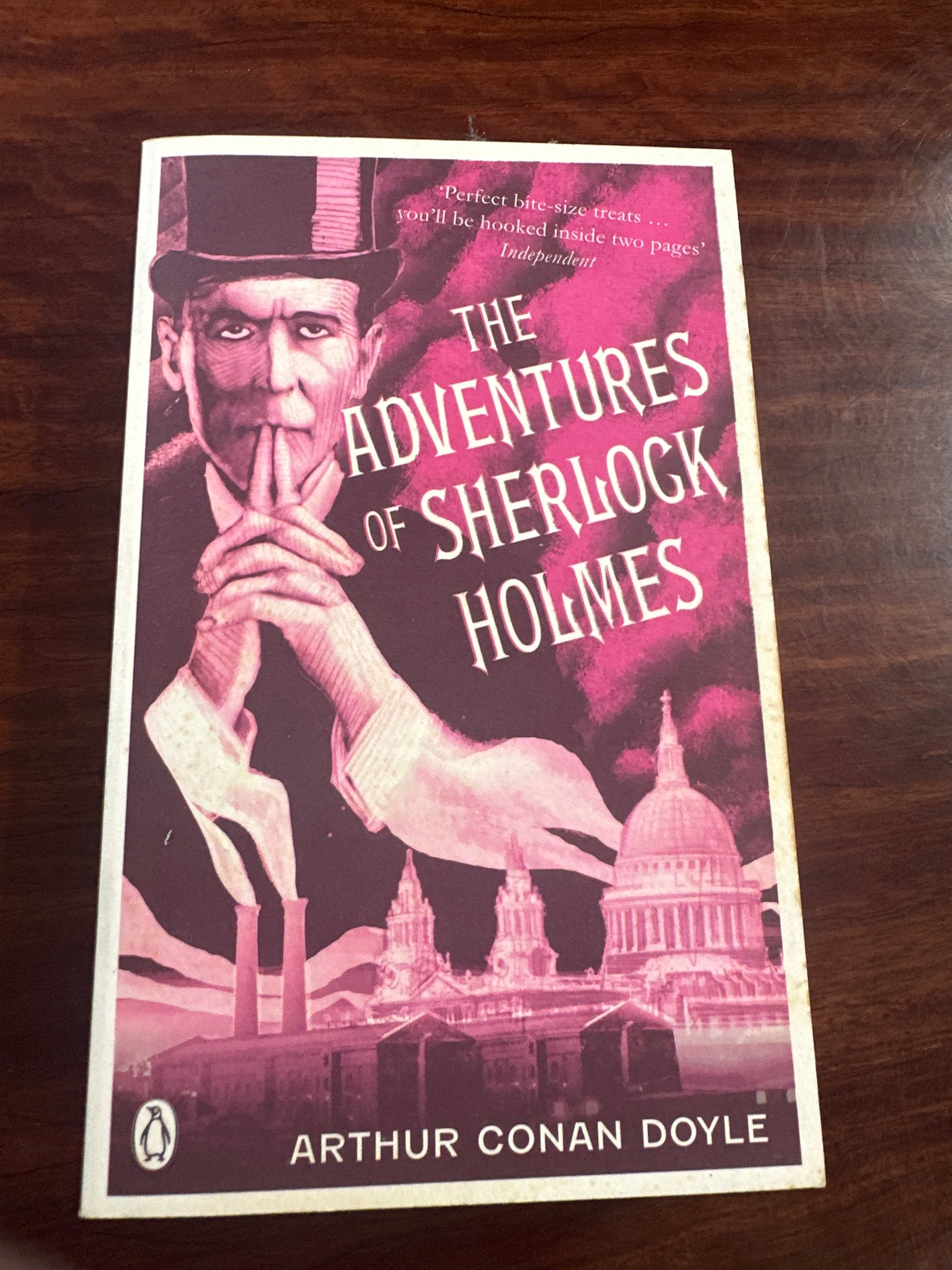 Book cover of 'The Adventures of Sherlock Holmes' by Arthur Conan Doyle on a wooden surface.