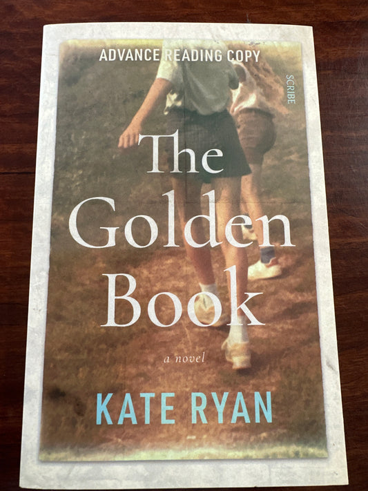Book cover of 'The Golden Book' by Kate Ryan on a wooden surface
