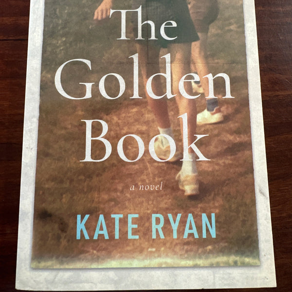 Book cover of 'The Golden Book' by Kate Ryan on a wooden surface