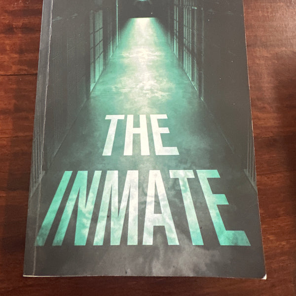 Book titled 'The Inmate' by Freida McFadden on a wooden surface