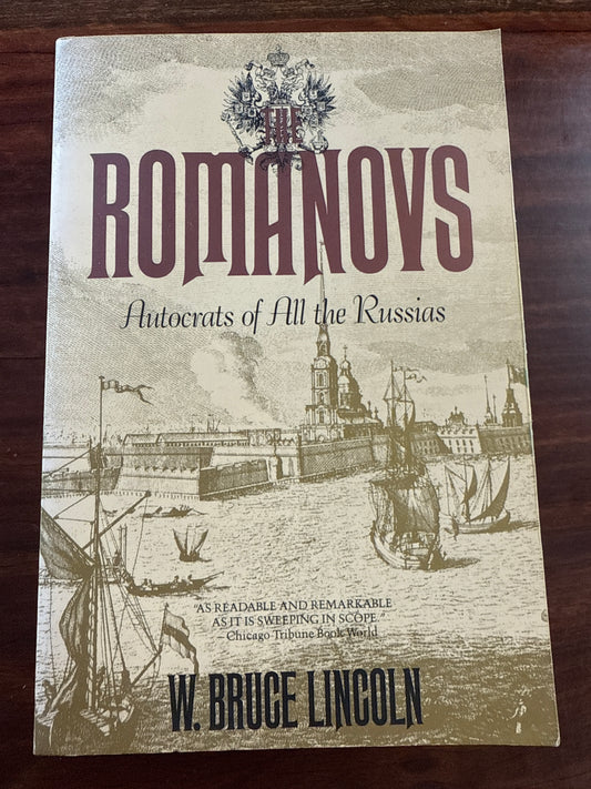 Book cover of 'Romanovs: Autocrats of All the Russias' by W. Bruce Lincoln on a wooden surface.