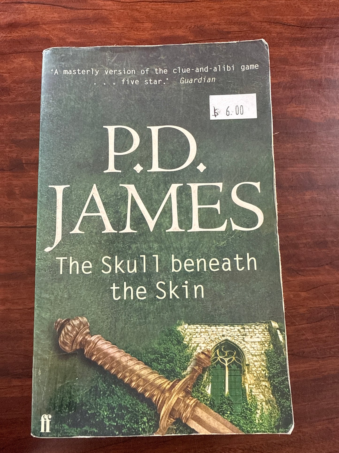 Book titled 'The Skull beneath the Skin' by P.D. James on a wooden surface