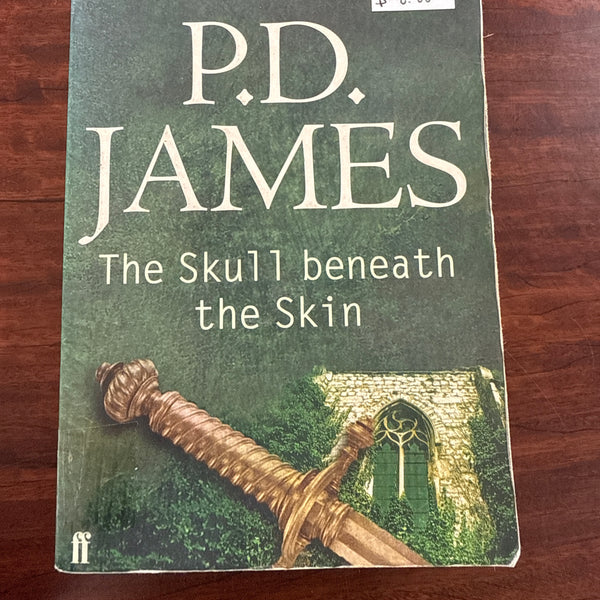 Book titled 'The Skull beneath the Skin' by P.D. James on a wooden surface