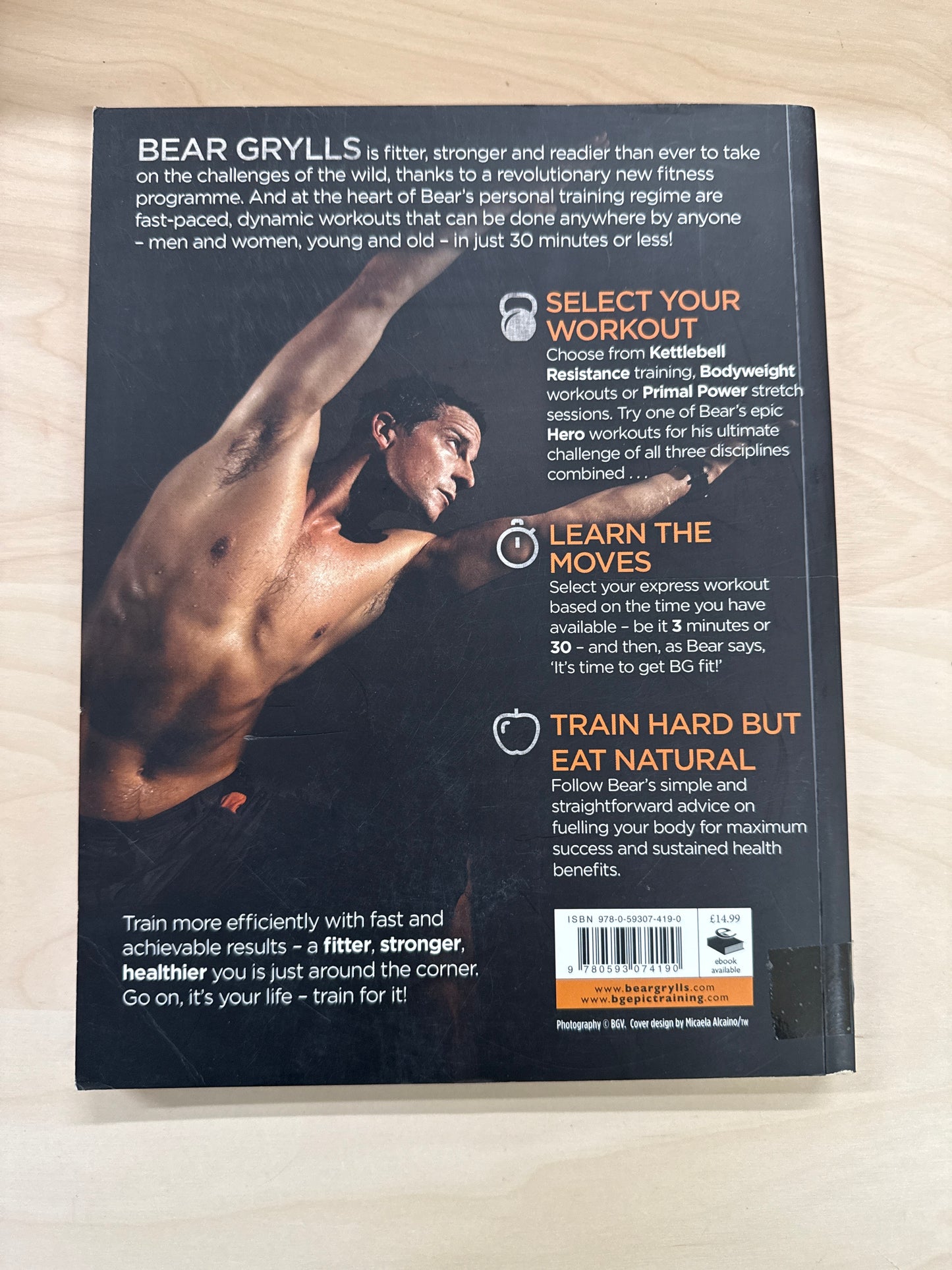 Book titled 'Train For It' by Bear Grylls on a wooden surface back cover